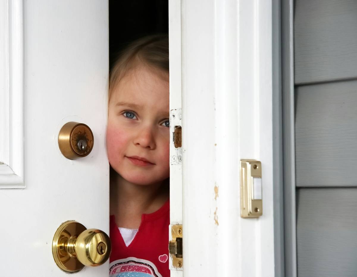 A little girl opening the door from inside.
